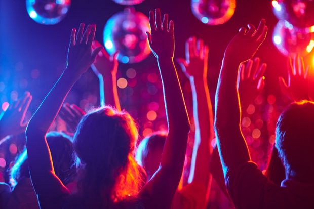 A group of people in a party setting with their hands in the air